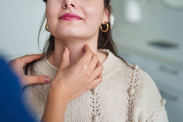 médecin vérifiant la thyroïde d’un patient - hypothyroidism photos et images de collection